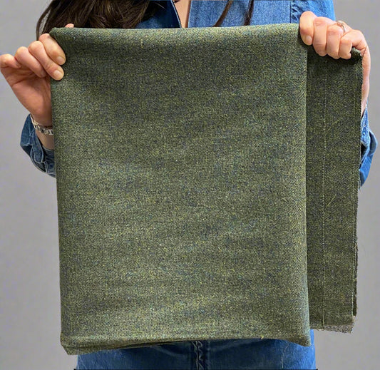 Person holding a piece of green tweed fabric